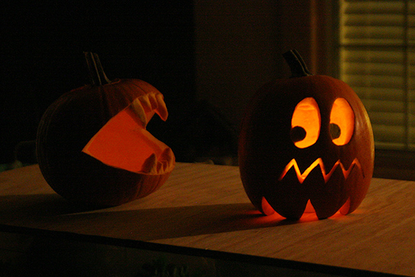 Pac-Man and Ghost pumpkins at night with candles.